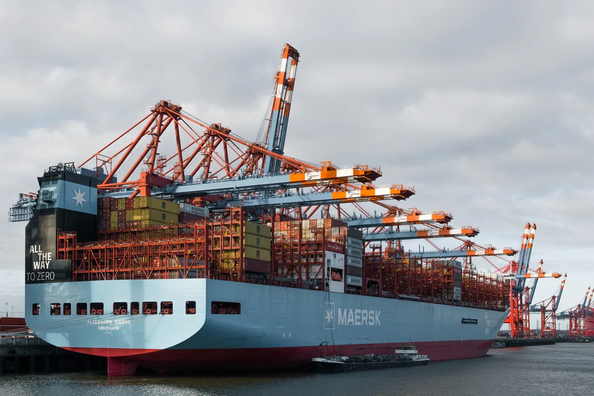 Container ship docked beneath freight cranes at Hamburg port